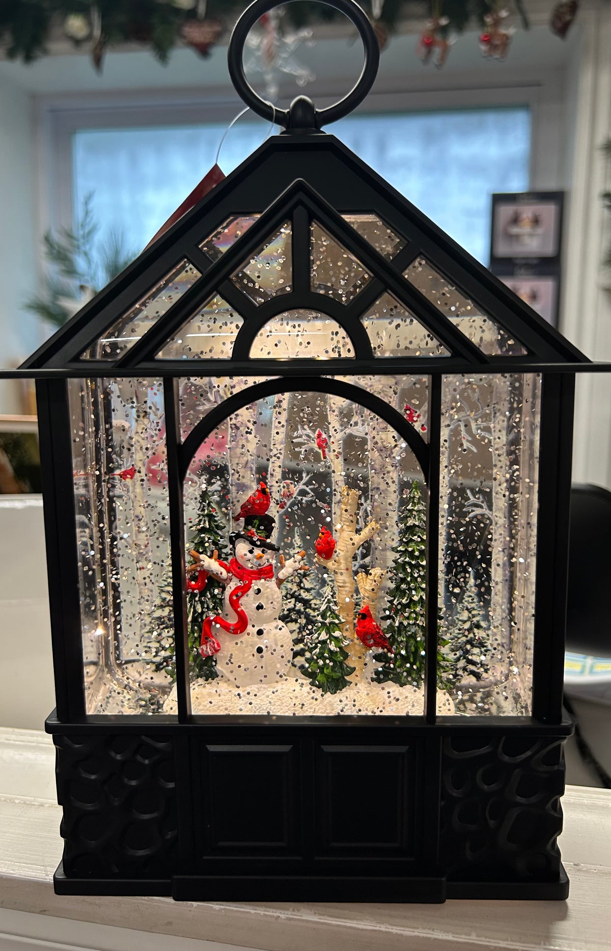 This beautiful winter scene will light up any room in your home. Featuring a Snowman with black hat and cardinal on head, birch trees and more cardinals inside black gazebo.