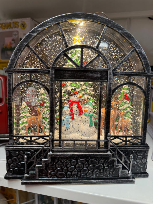 Experience the wonder of winter with our Greenhouse With Woodland Snowman Lighted Water Lantern. This enchanting globe features a delightful snowman and his deer friends, surrounded by sparkling snow-capped trees. The swirling glitter brings this magical scene to life, making it the perfect addition to your festive décor. Plus, with a USB cord included, lighting up this charming lantern couldn't be easier.